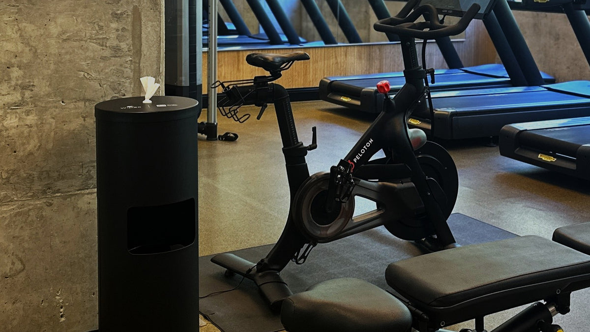 Modern commercial gym with cleaning wipe dispensers on the equipment floor