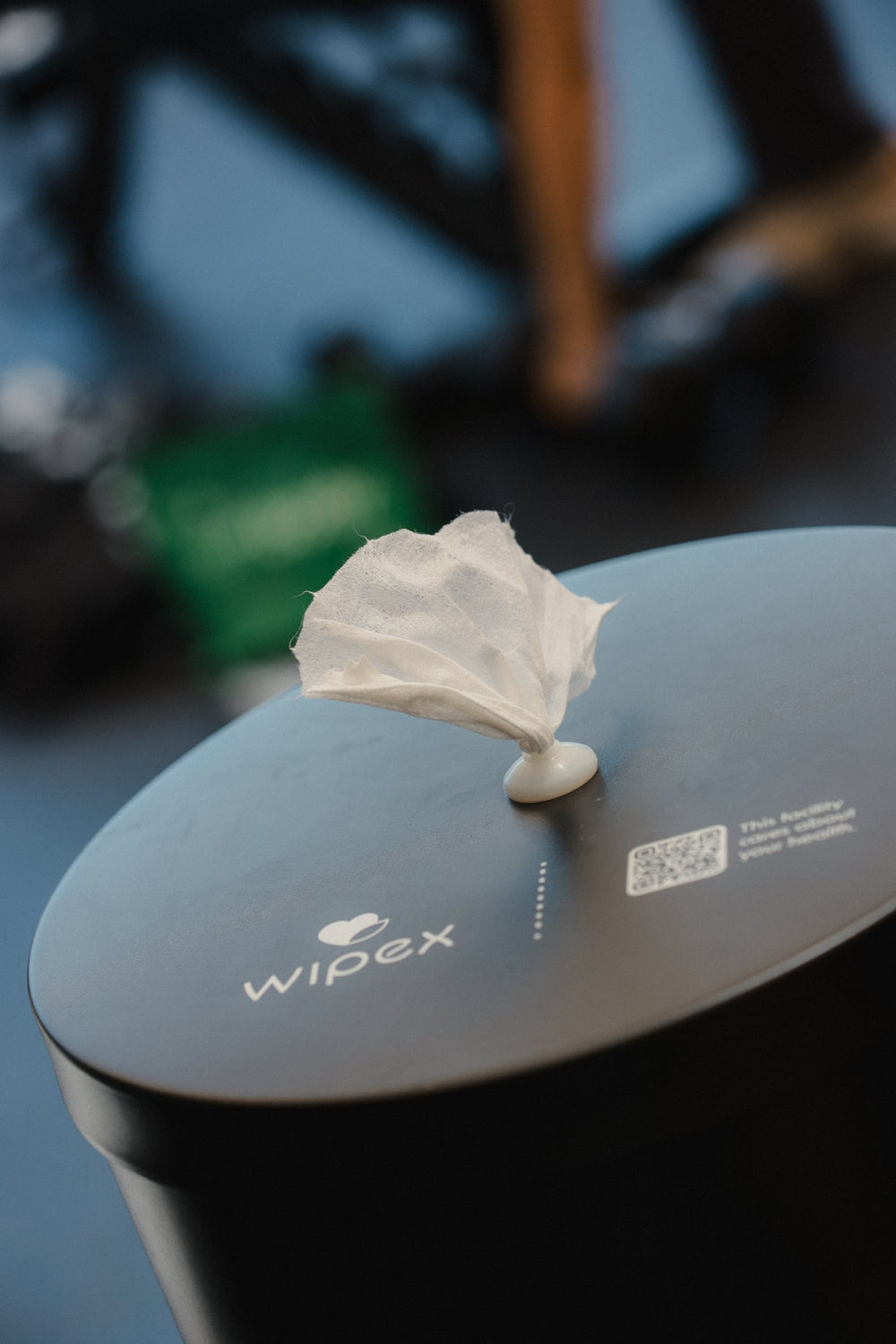 Wipex matte black floor dispenser with a wipe ready on a gym floor